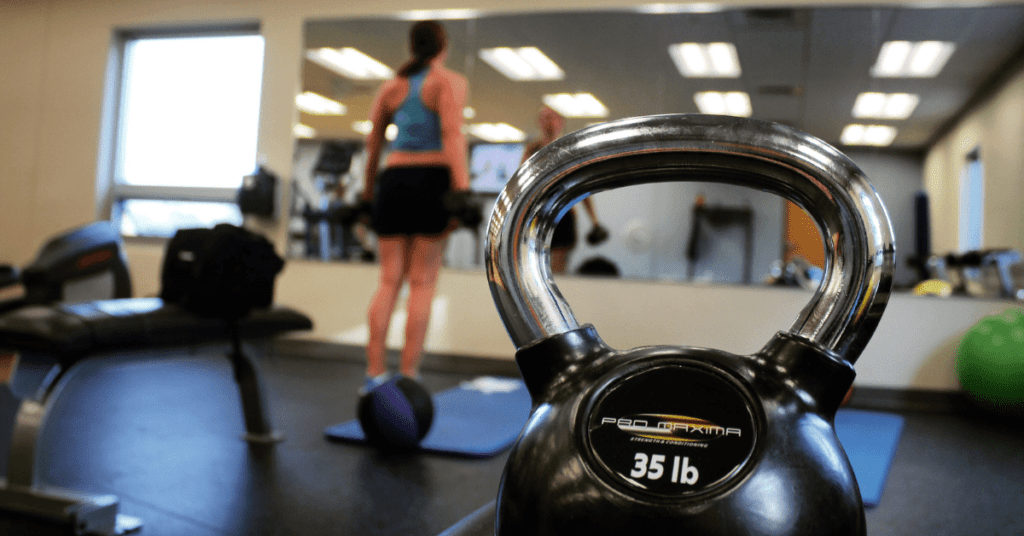 woman in a weight room exercising in front a mirror