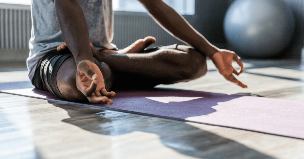 man sitting cross legged on yoga matt