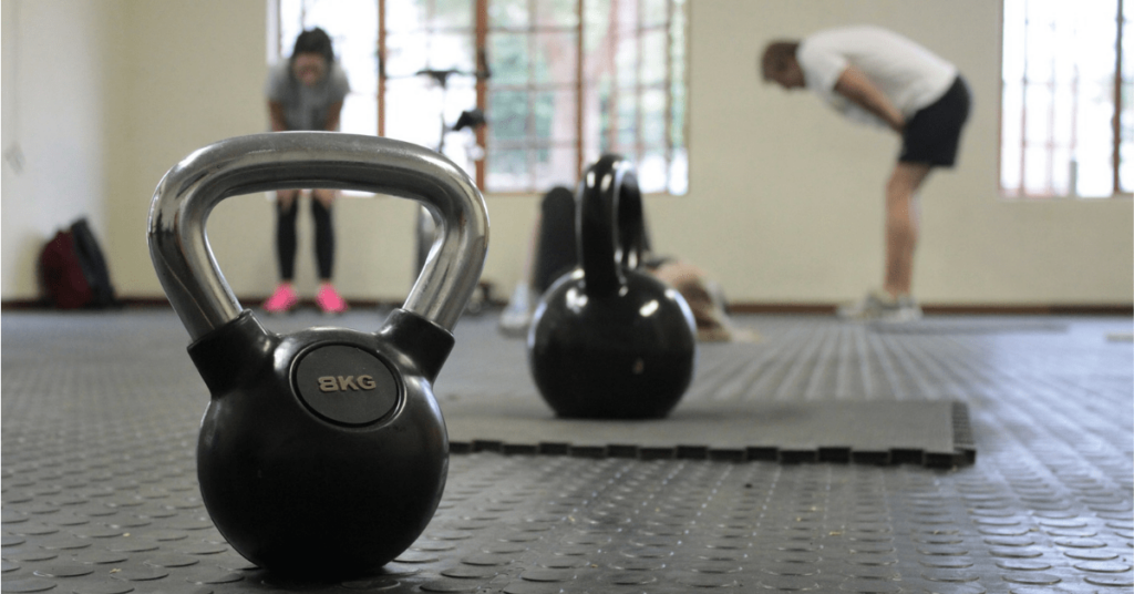 two kettle bells in a gym with people in the background