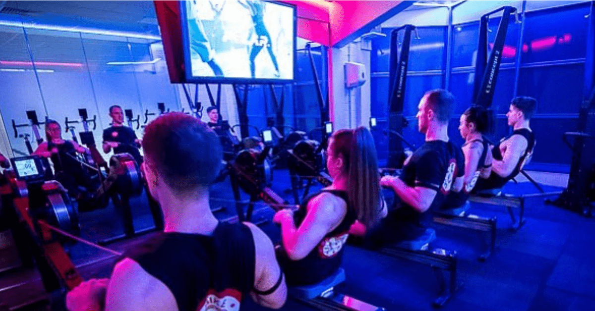 BikeRowSki class on rowing machines in a neon gym