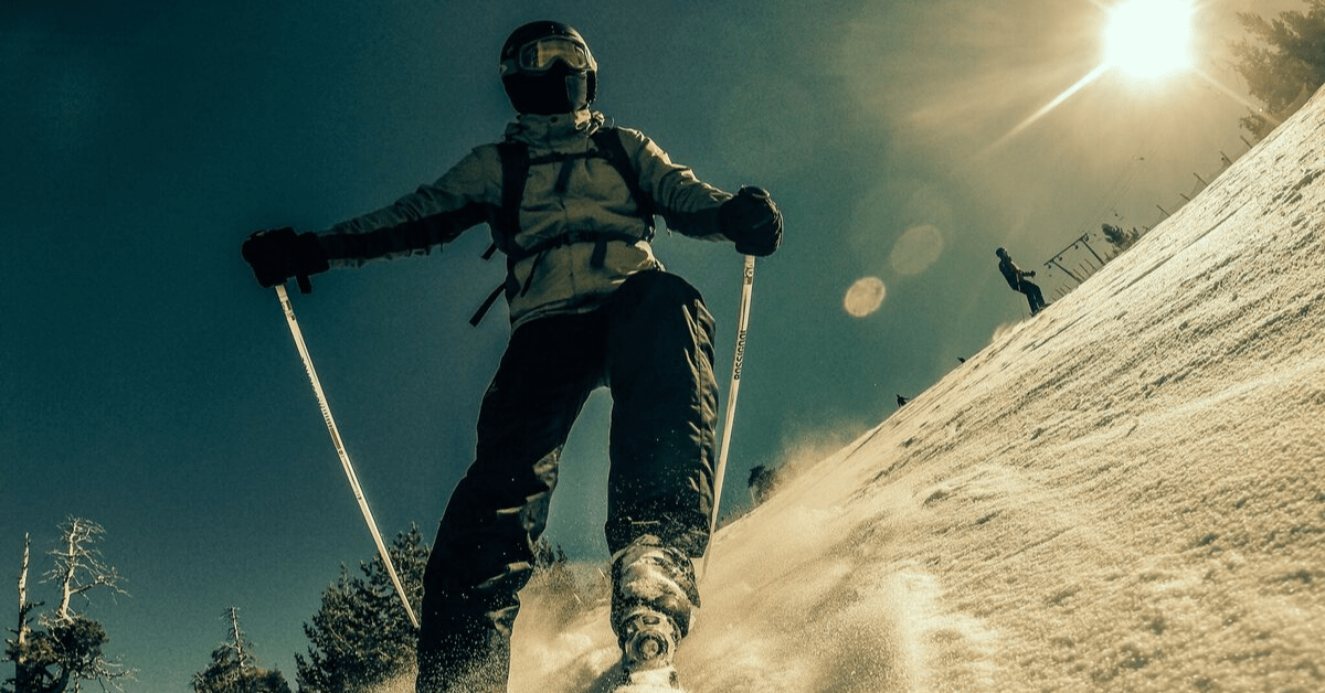 a skier turning on a snowy hill with the sun beaming down