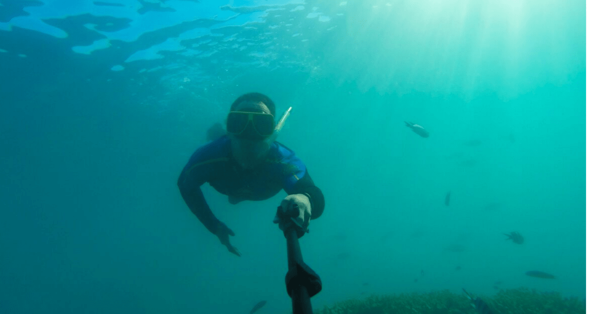 snorkeler in blue water with camera 