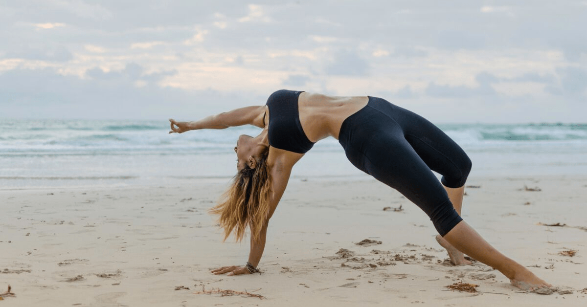 woman performing yoga pose on a beach 