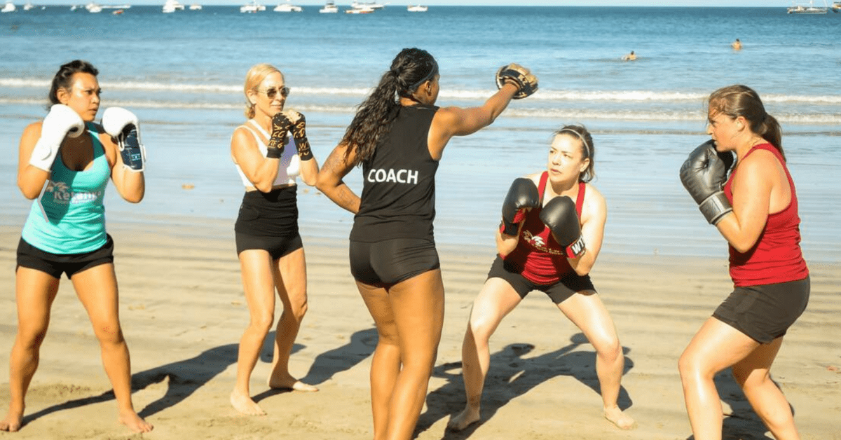 women doing a boxing class on the beach