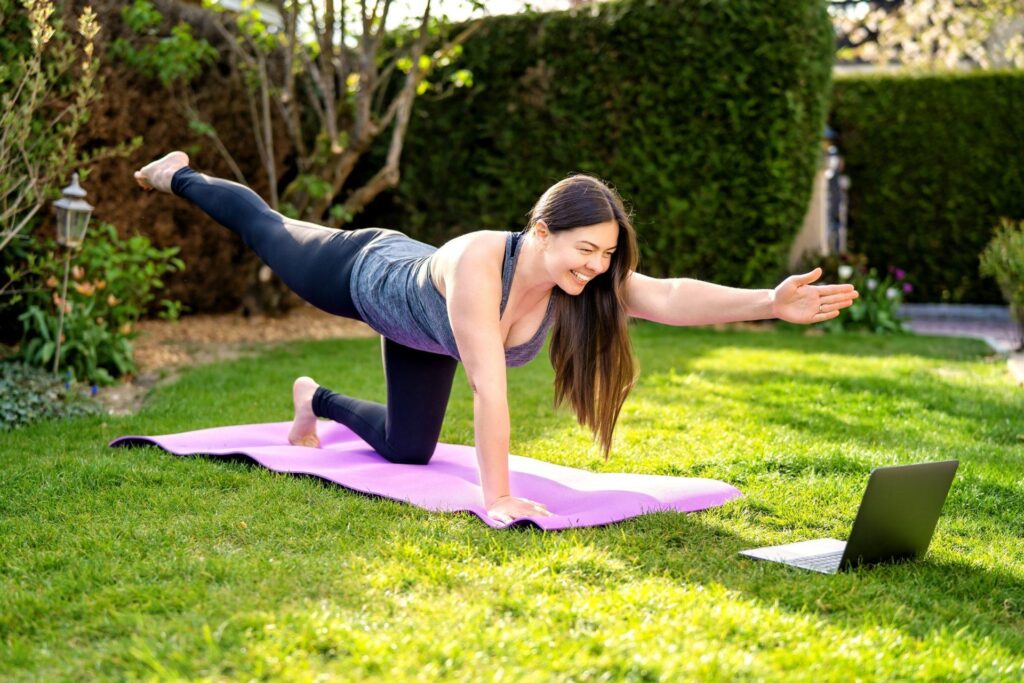 happy-smiling-woman-practicing-pilates-lesson-online-in-garden-outdoors-during-quarantine-doing-sport_t20_lLJre2